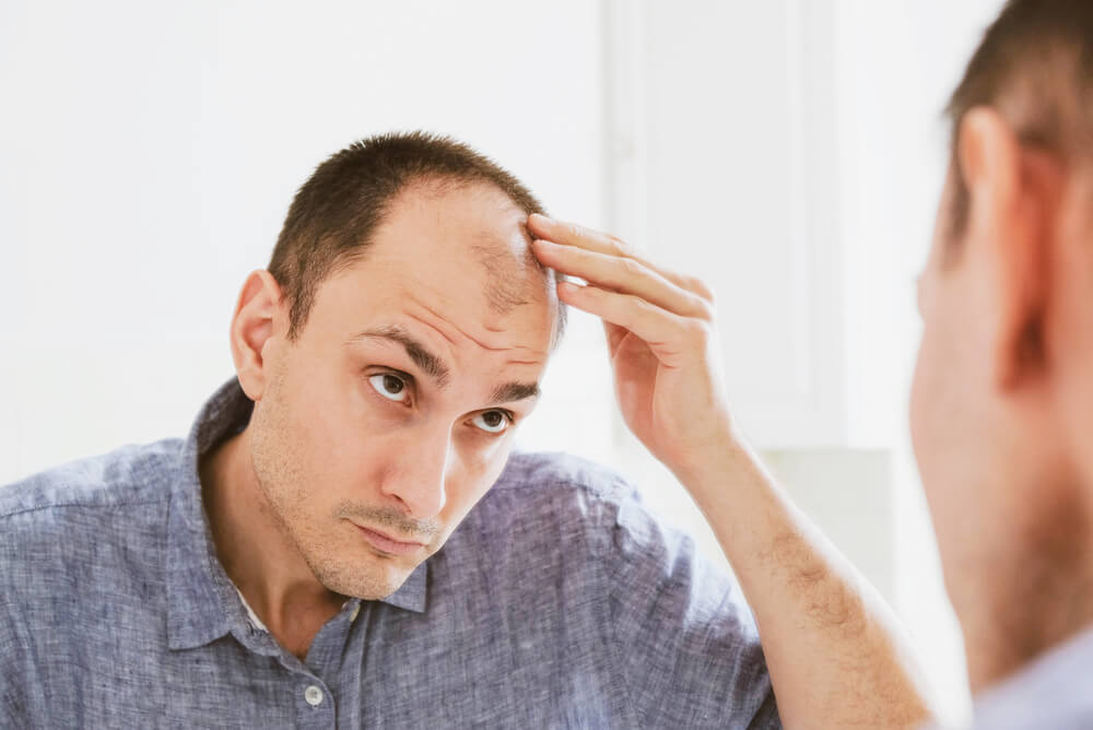 a man checking a bald spot in the mirror